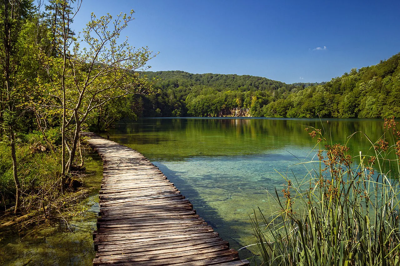 A wooden walkway along the shore of a large lake in Plitvice Lakes National Park, Croatia