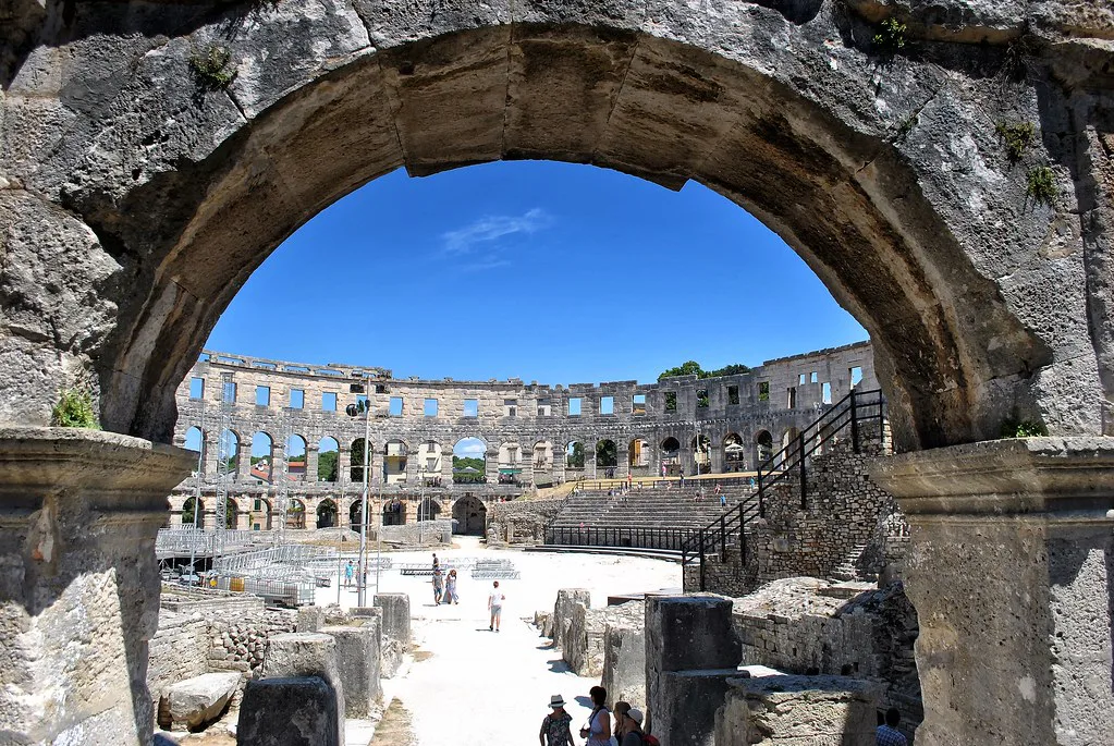 The arcades of the Roman amphitheatre in Pula seen through a stone arch