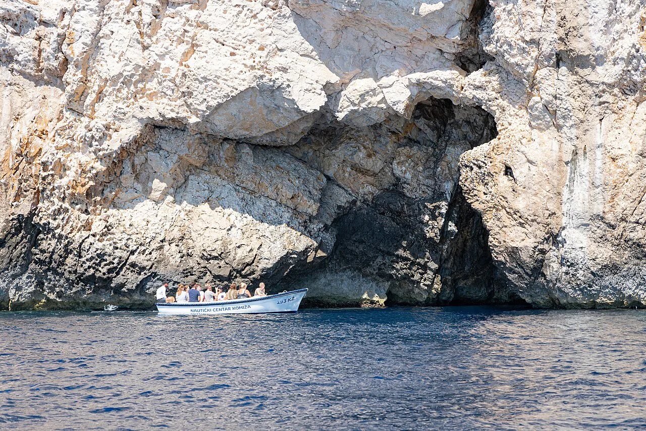 A small tourist boat at the rocky entrance to the Blue Cave on Biševo, Vis