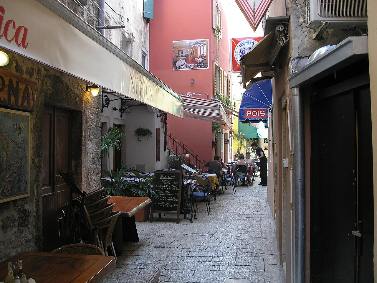 A narrow stone street with café tables in the old town of Rovinj