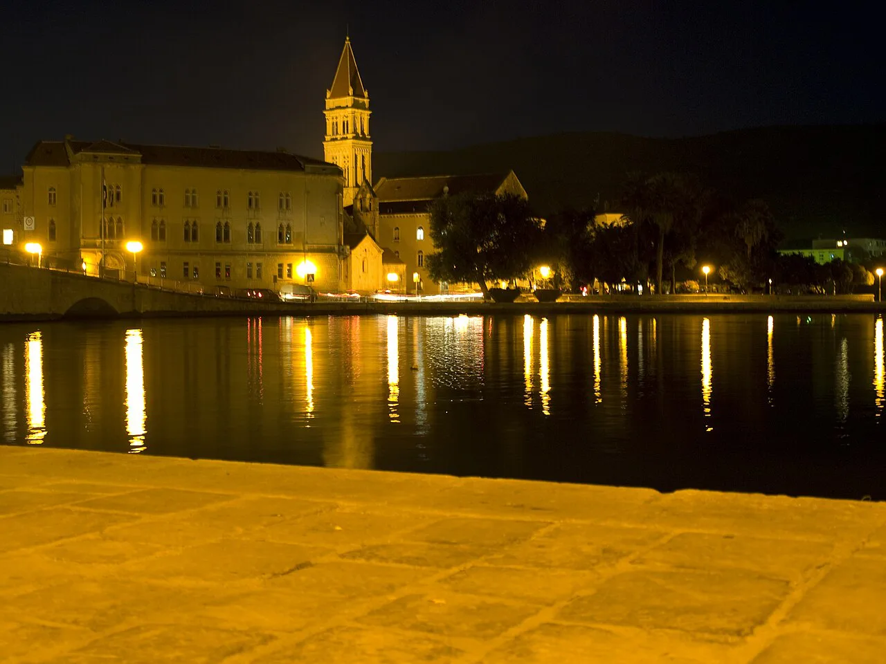 The Cathedral of St Lawrence bell tower lit up at night above the Trogir waterfront, Dalmatia