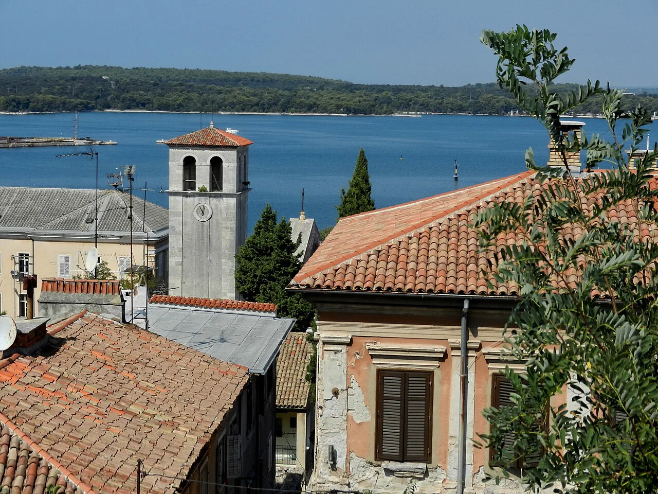 The cathedral bell tower above rooftops and the harbour in Pula