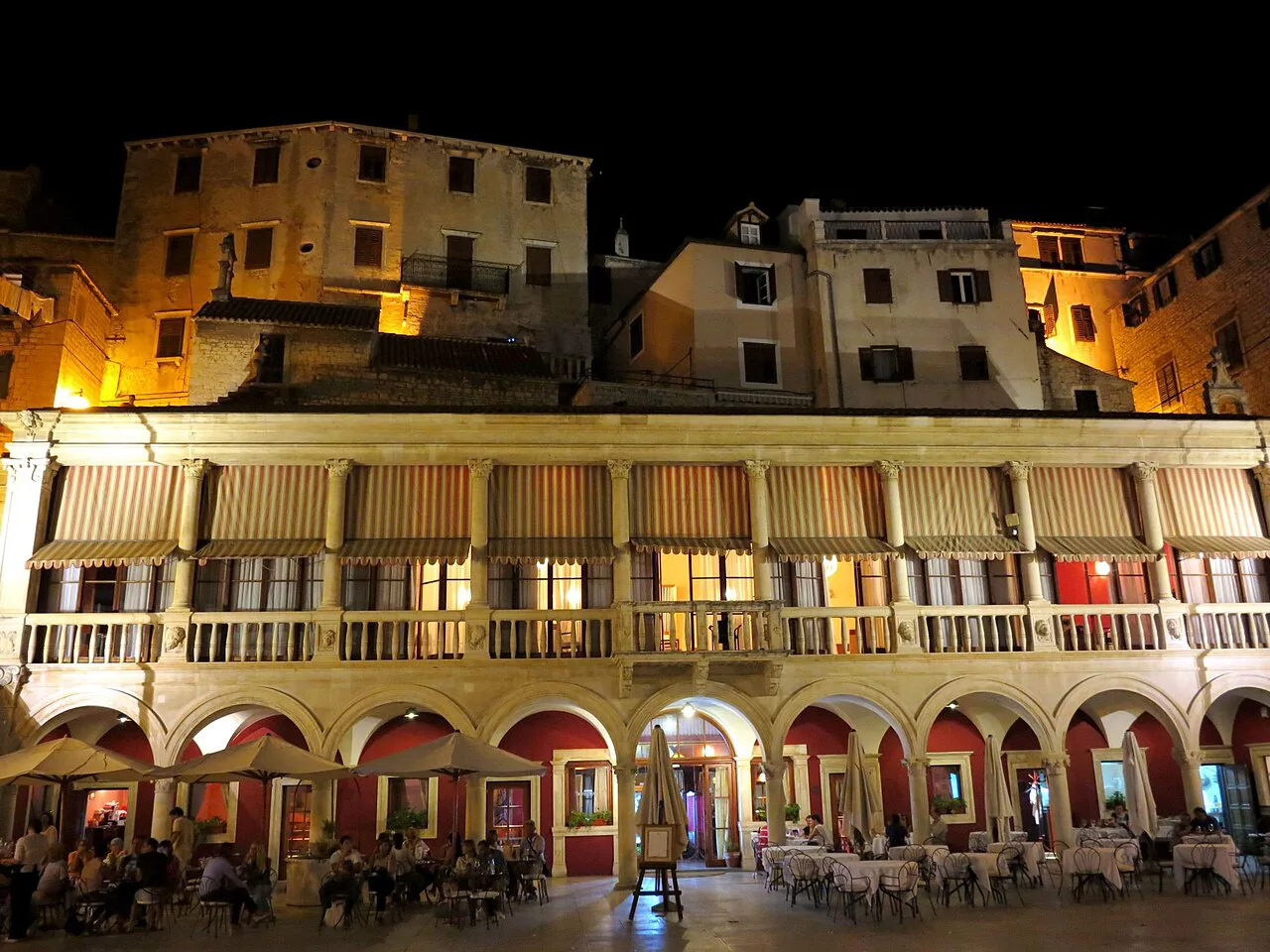 An arcaded loggia on the cathedral square in Šibenik, lit at night
