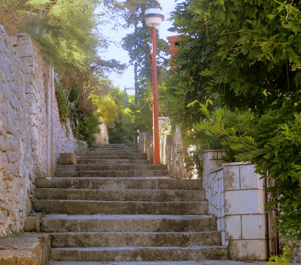 Stone steps climbing between walls and greenery in Korčula, Croatia
