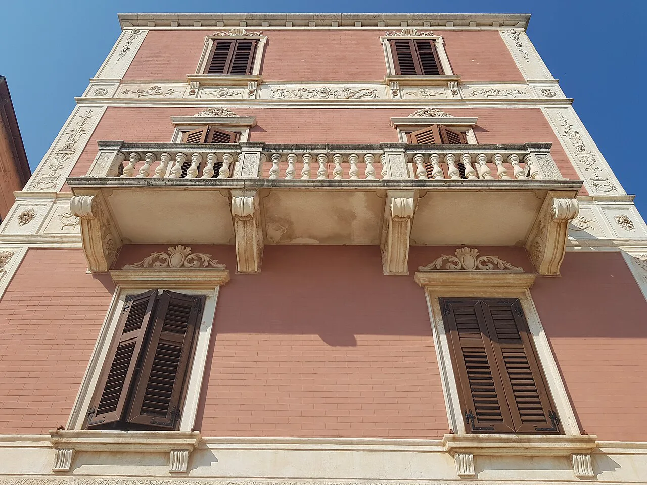 A pink building façade with a balcony facing the harbour in Hvar Town, Croatia