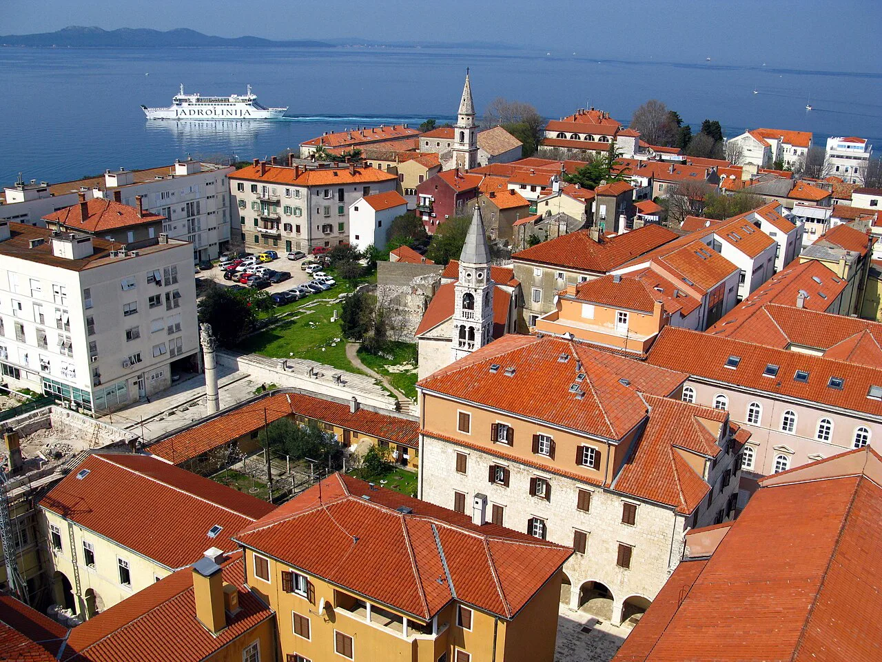 Red roofs of Zadar's old town seen from the cathedral bell tower, with a ferry offshore, Croatia