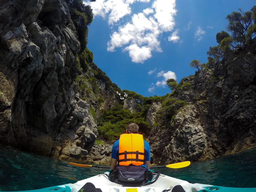 A kayaker paddling between rocky cliffs off the island of Koločep, Croatia