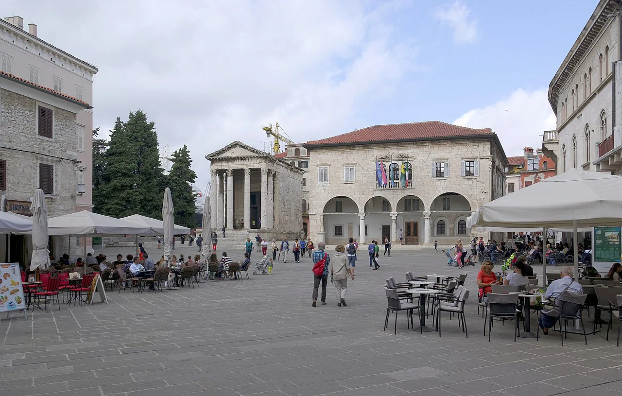 Café tables on the forum in Pula with the Temple of Augustus and town hall.