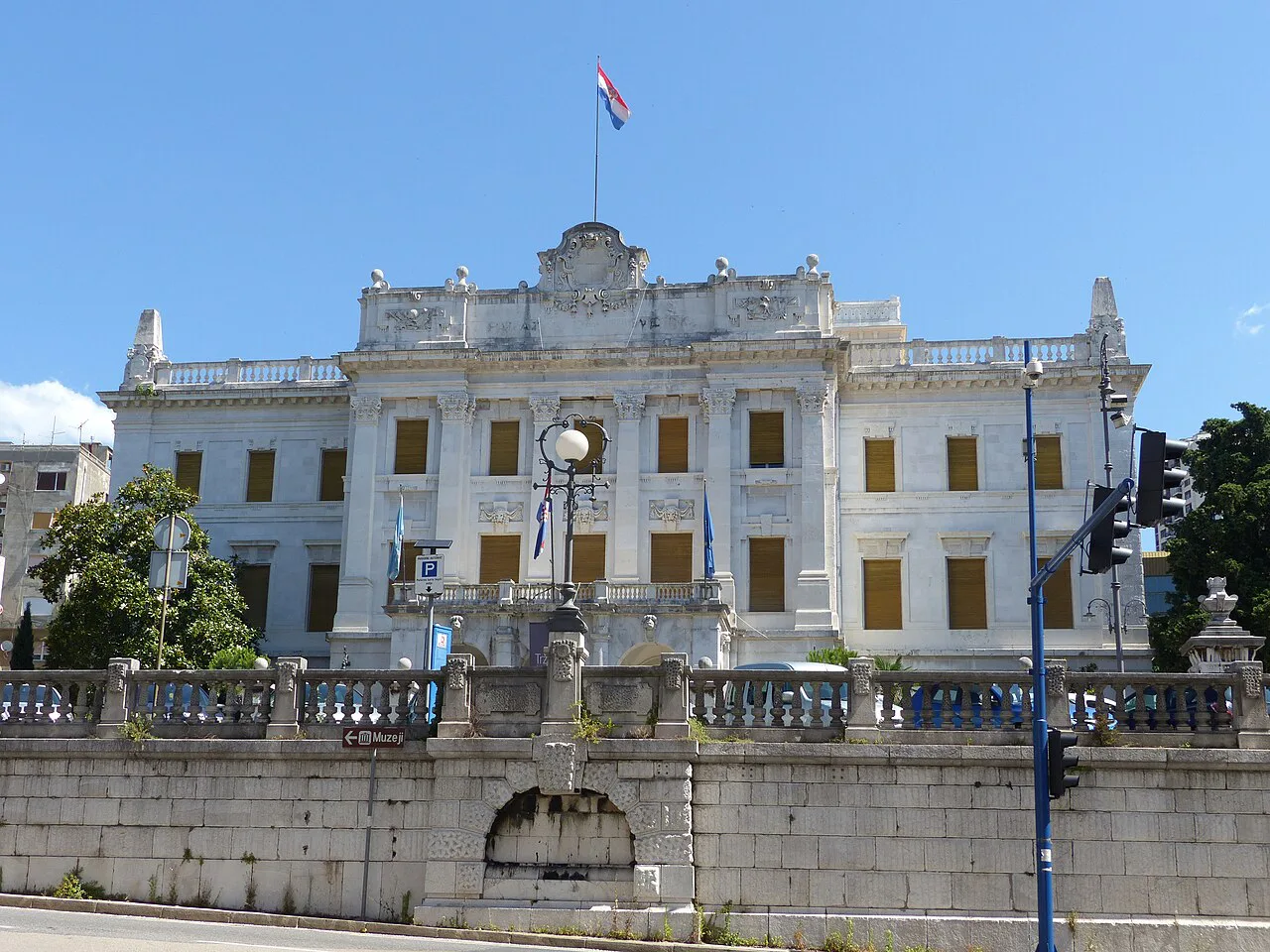The white facade of the Governor's Palace above a stone wall in Rijeka