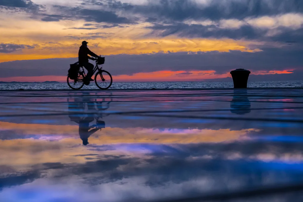 A cyclist crossing the Greeting to the Sun installation in Zadar at sunset