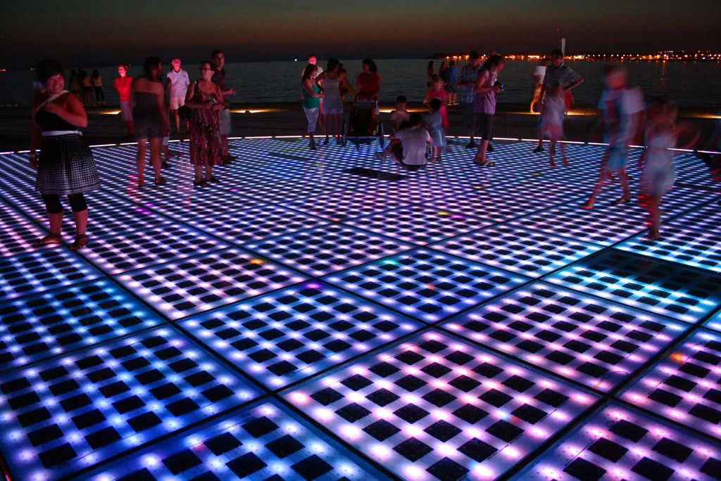 People walking on the illuminated Greeting to the Sun panels in Zadar