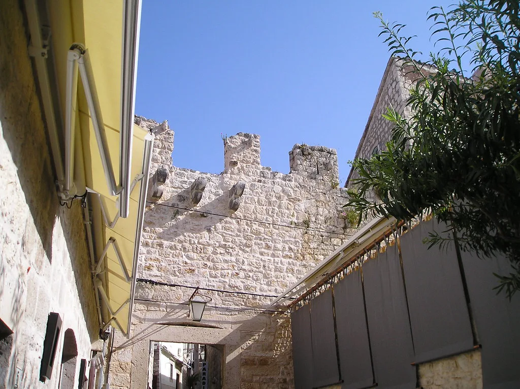 Crenellated stone city walls rising behind houses in Hvar Town