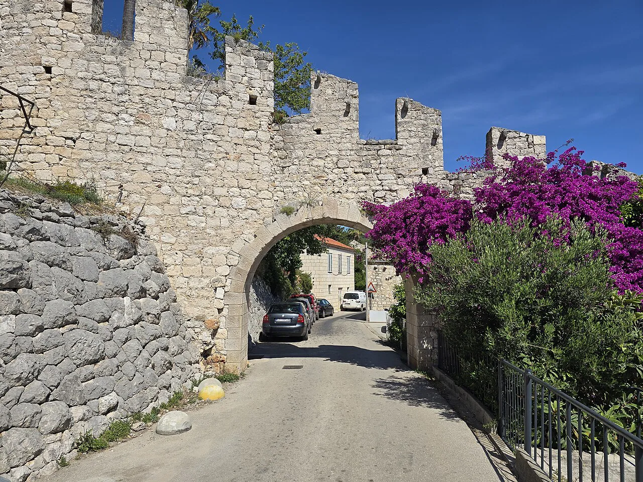 A gate in the medieval city walls of Hvar with flowering bougainvillea beside it