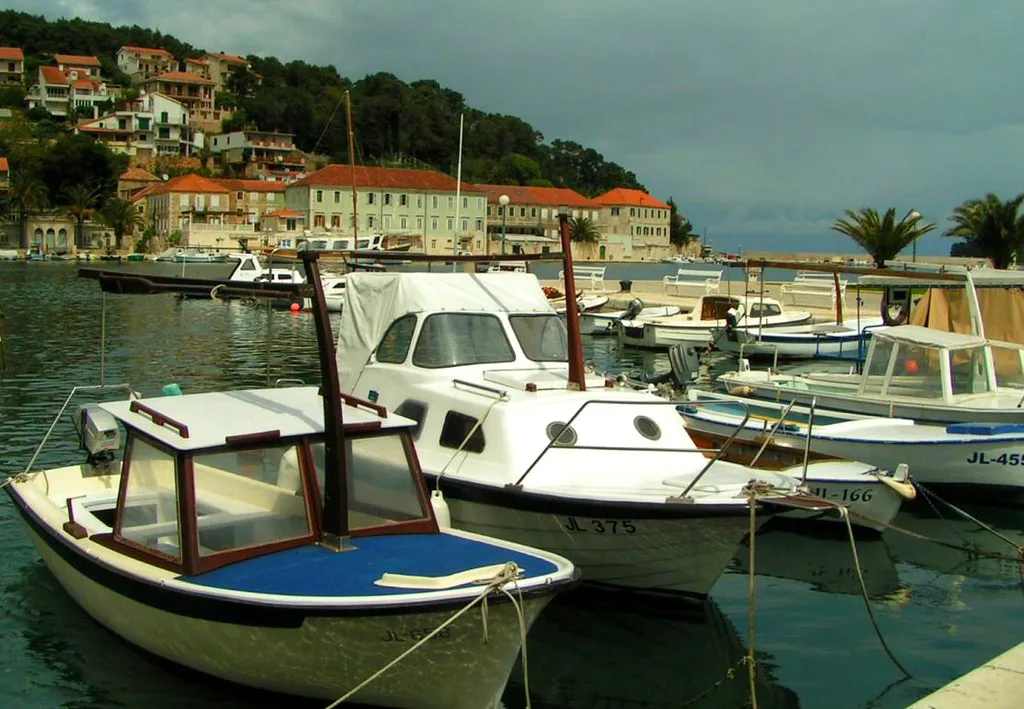 Small boats moored in the harbour of Hvar below houses on the hillside
