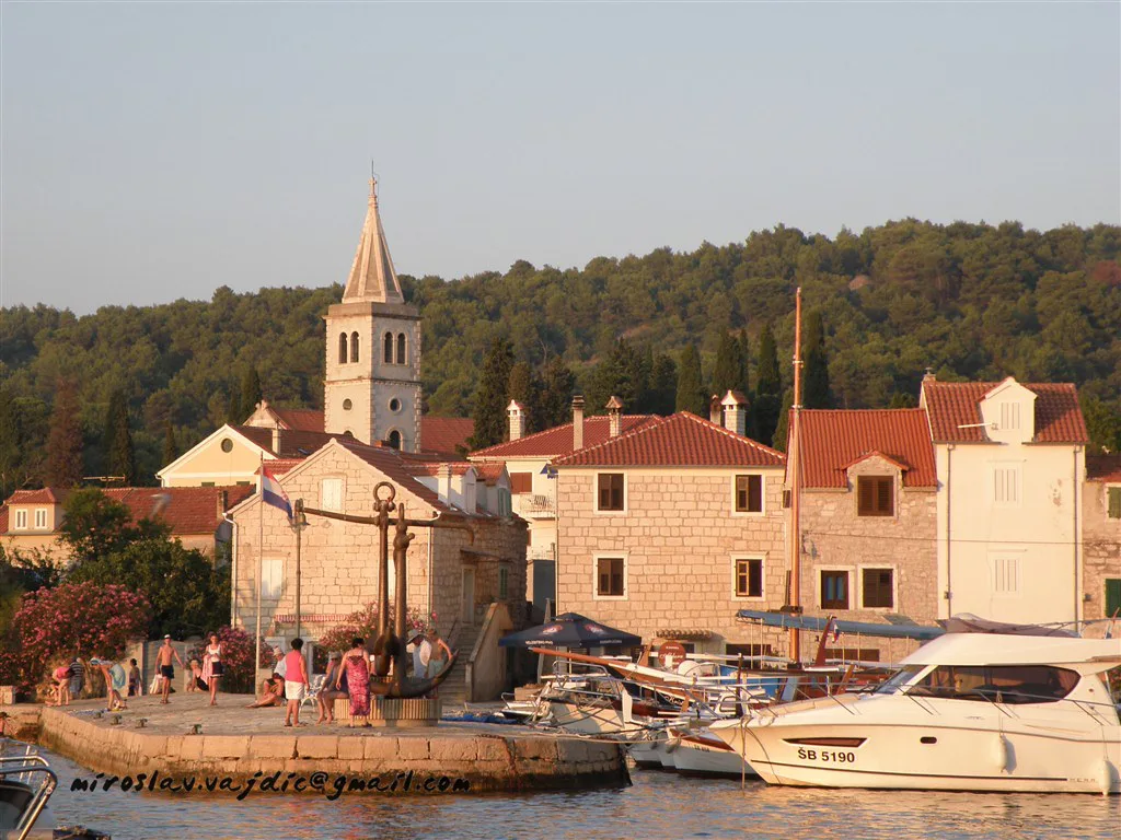 Stone houses, a bell tower and moored boats on the island of Zlarin.