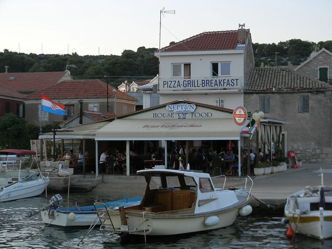Small boats moored beside a waterfront restaurant in the harbour of Kaprije, Šibenik