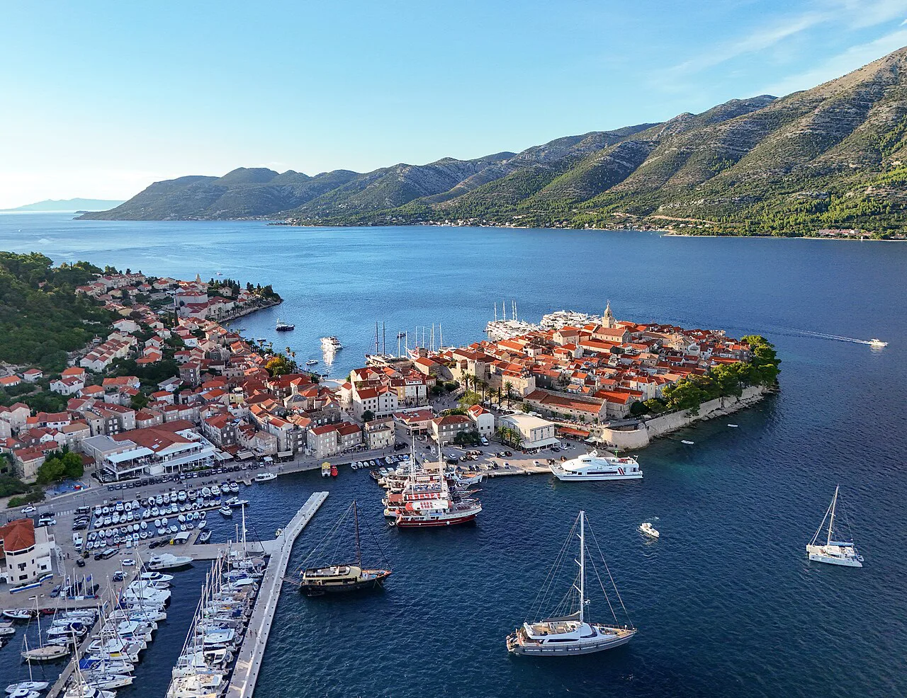 Aerial view of Korčula Old Town and its harbour with boats moored alongside.