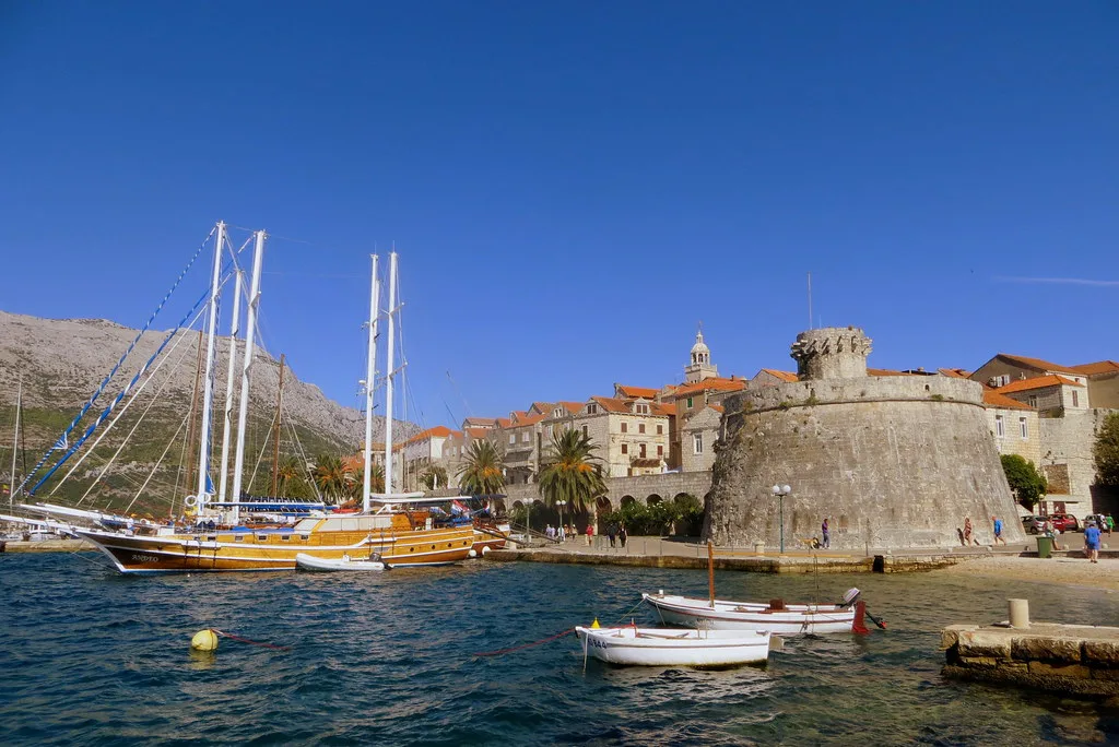 Sailing boats moored below a round defensive tower in Korčula Town.