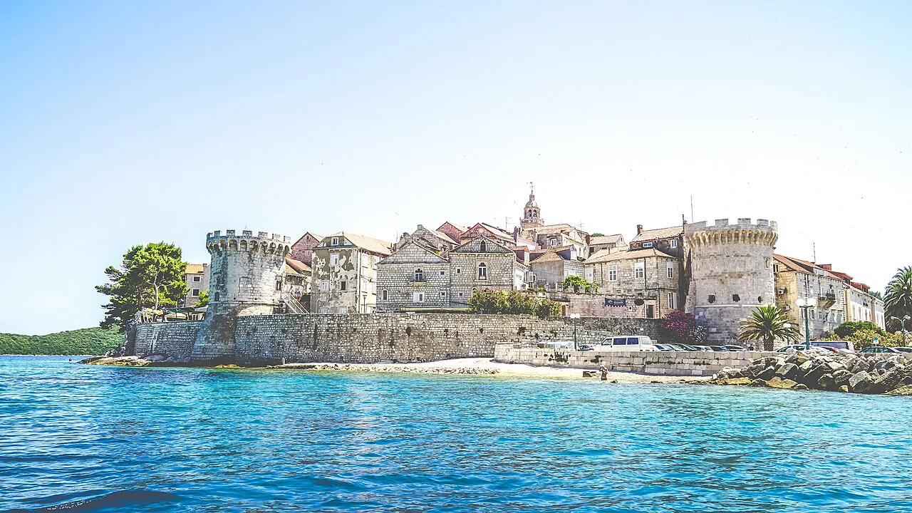 The walls and towers of Korčula Old Town above clear blue water