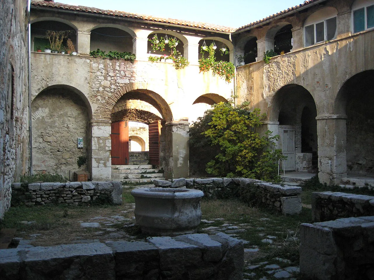 An arcaded stone courtyard with a central well in Kraljevica, Kvarner