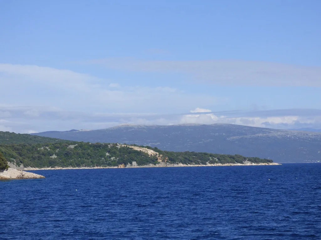 The wooded coastline of the island of Krk across blue water, Kvarner