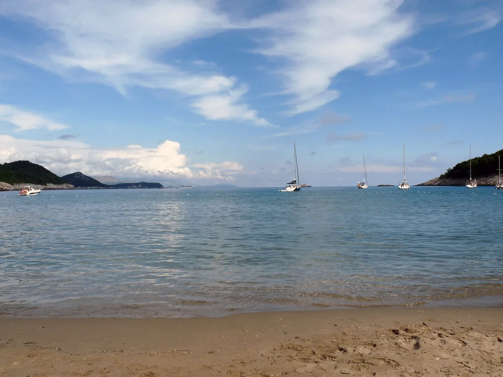 A sandy beach and calm sea with sailing boats at Lopud, Southern Dalmatia