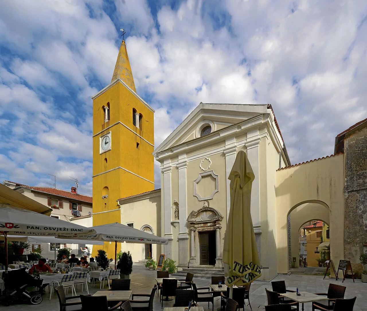 St George's Church with its yellow bell tower beside a square in Lovran.
