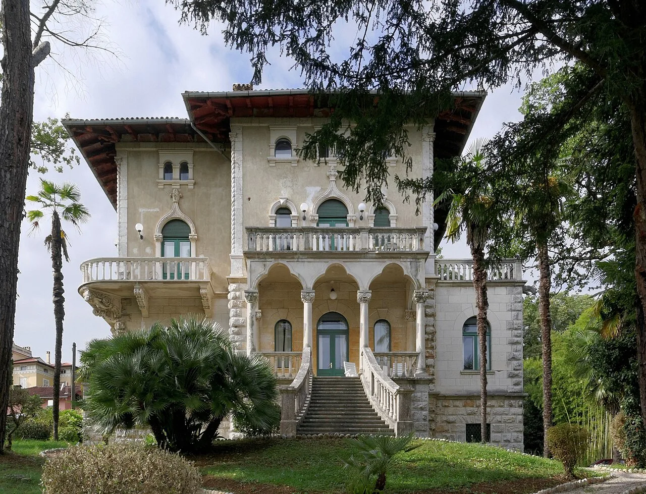 An ornate villa among palm trees beside the Lungomare at Ika.