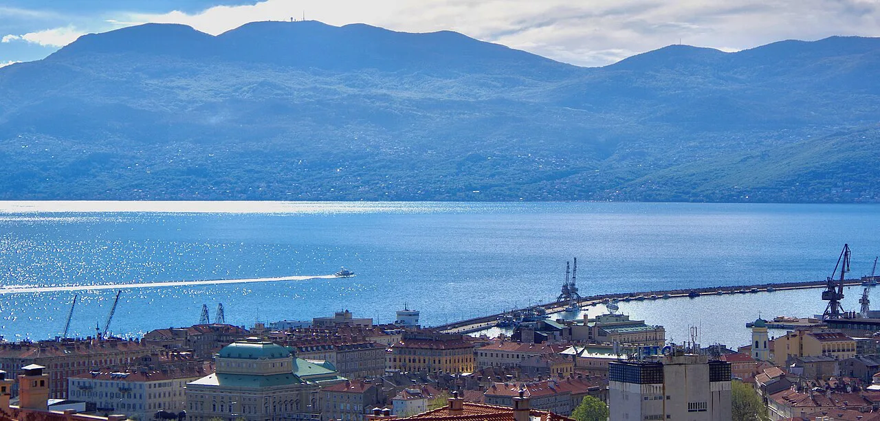 Central Rijeka and its harbour breakwater with Učka mountain across the bay