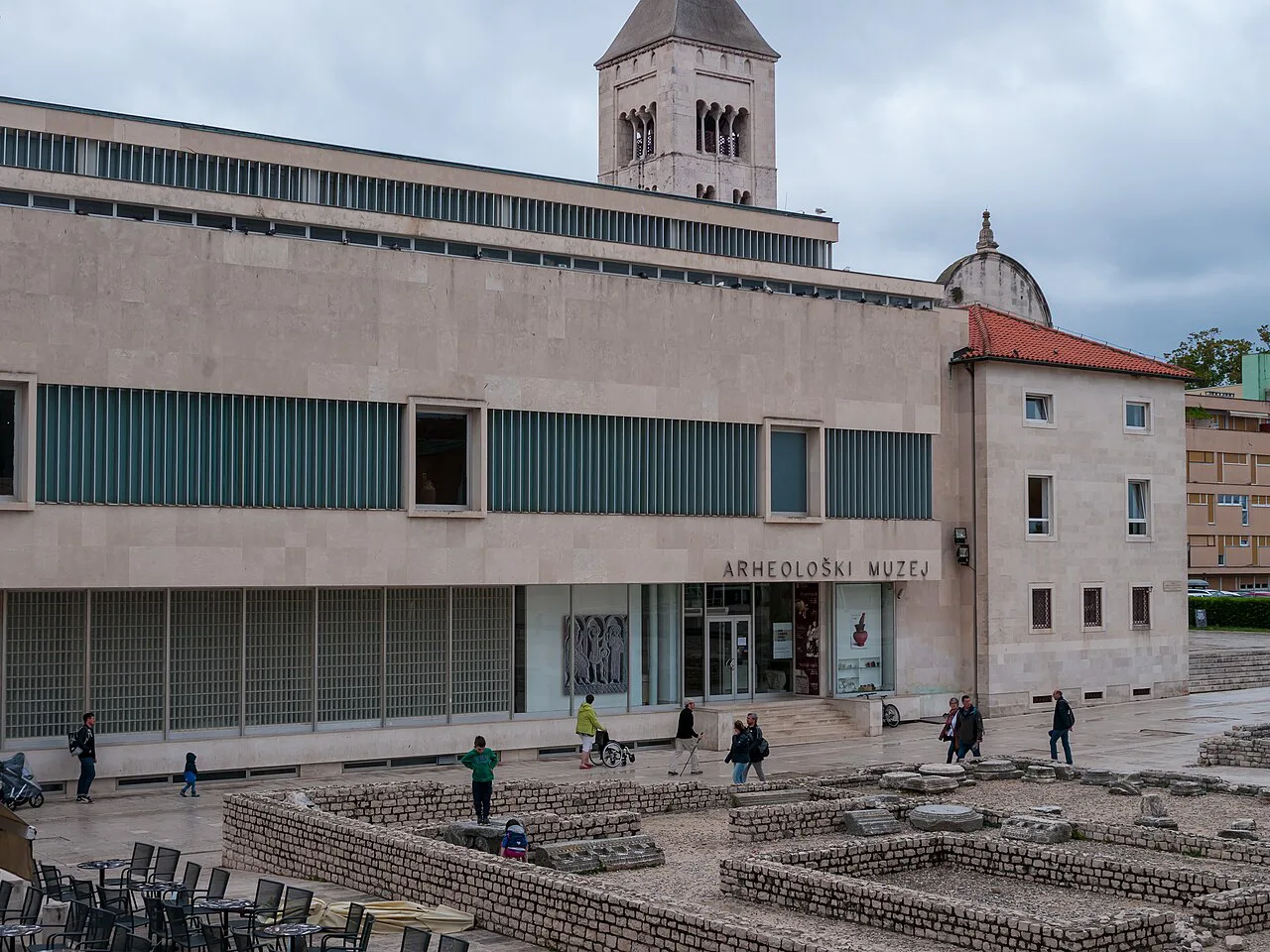 A museum building beside a stone bell tower in the Old Town of Zadar