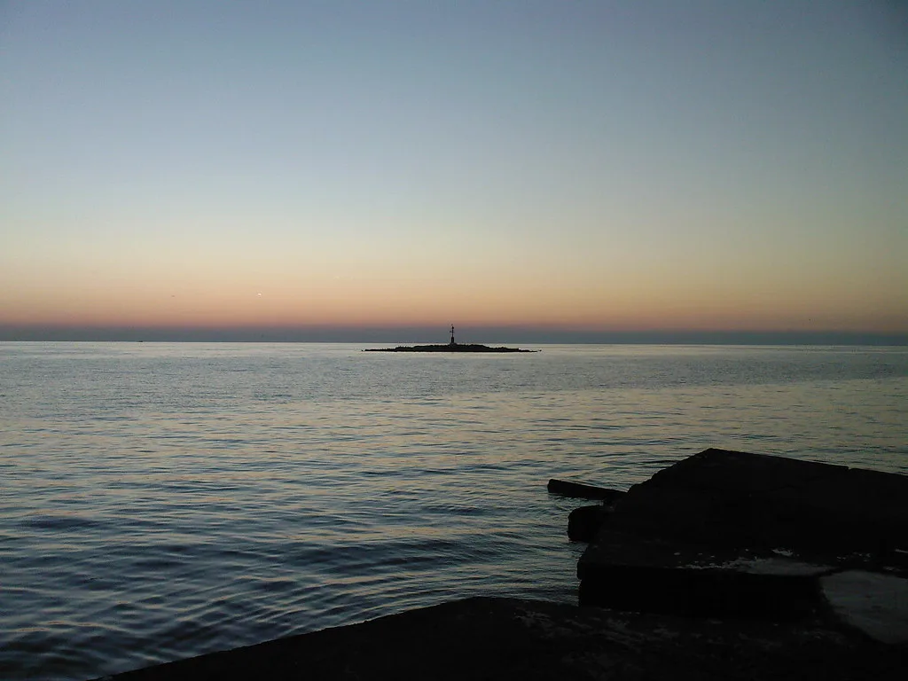 Calm sea and a small islet off the coast of Poreč at dusk