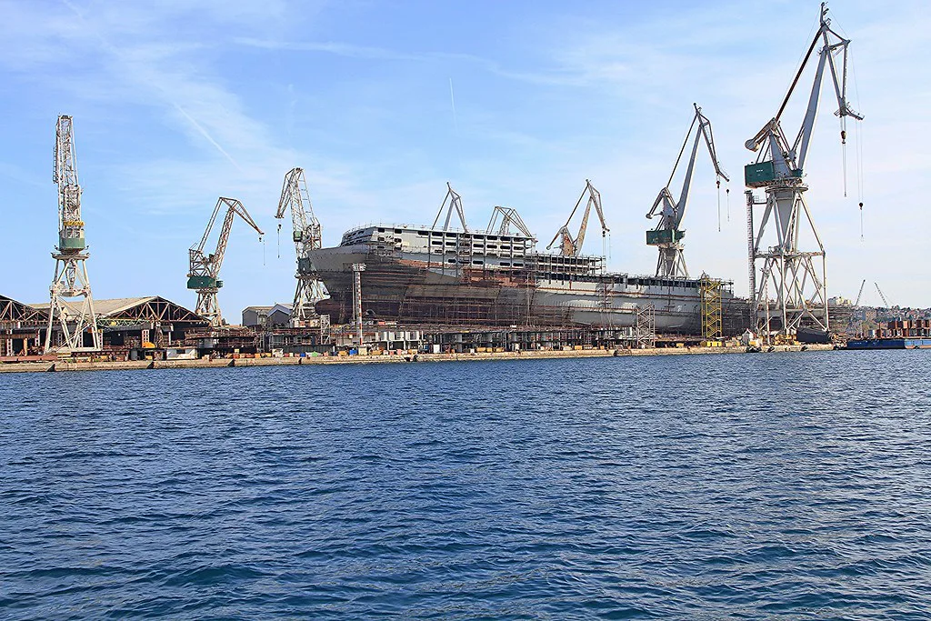 Shipyard cranes rising above the harbour waters in Pula