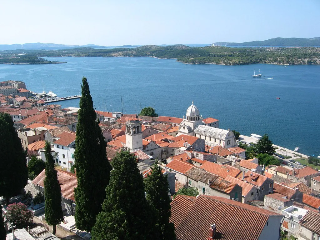 Red rooftops and a domed cathedral in Šibenik beside the sea channel