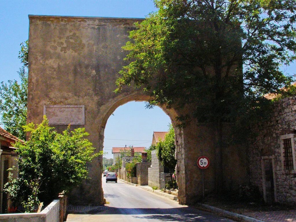 A stone gateway with an arched passage leading into the old town of Nin, Dalmatia