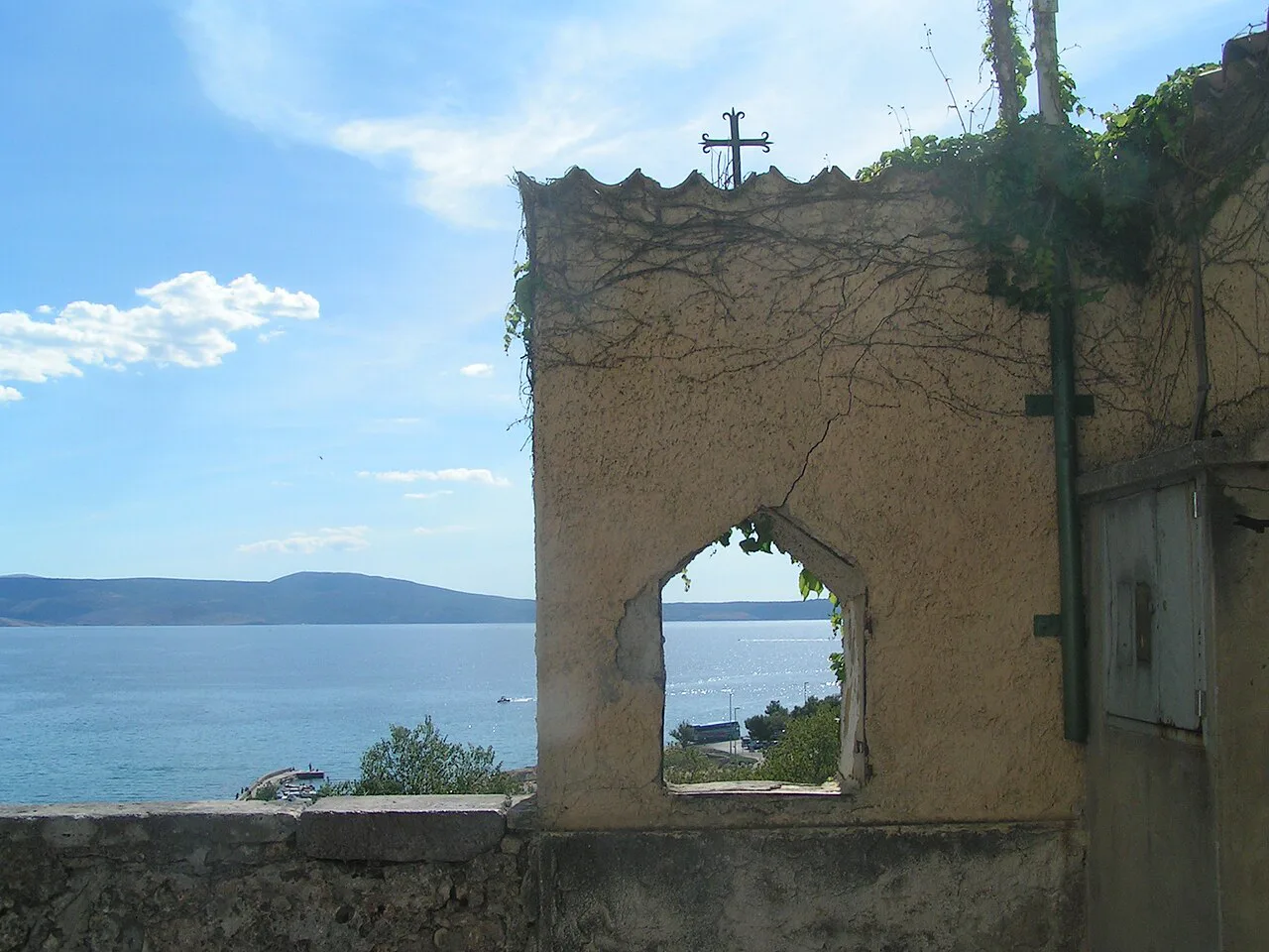 A ruined stone wall with an arched window framing the sea at Novi Vinodolski, Kvarner