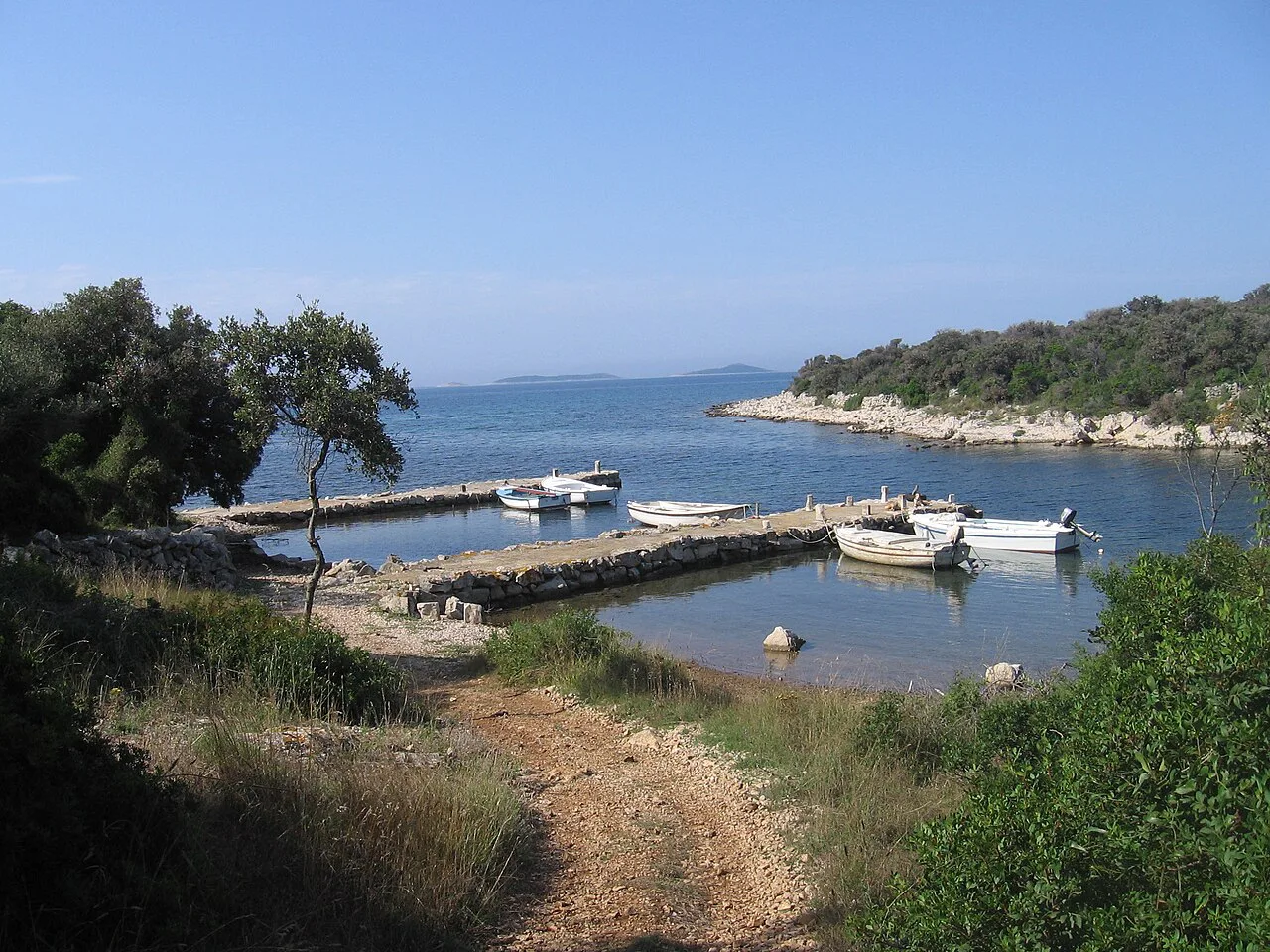Small boats moored at a stone jetty in the port of Banjve on Olib, Zadar