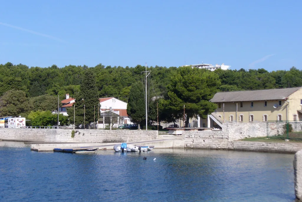 A small harbour with boats and wooded shoreline on the coast at Pula