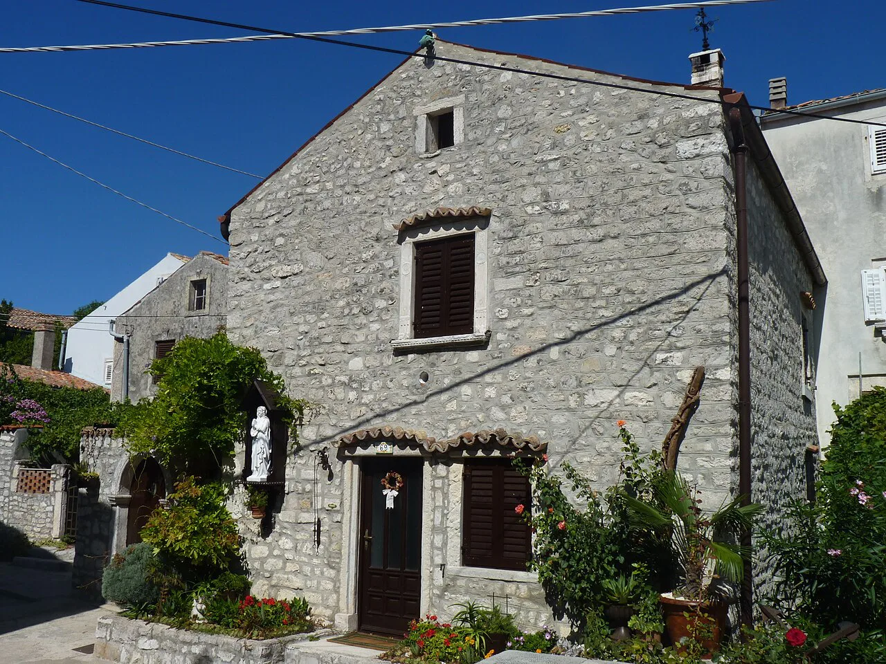 A two-storey stone house with green shutters in the town of Osor, Kvarner