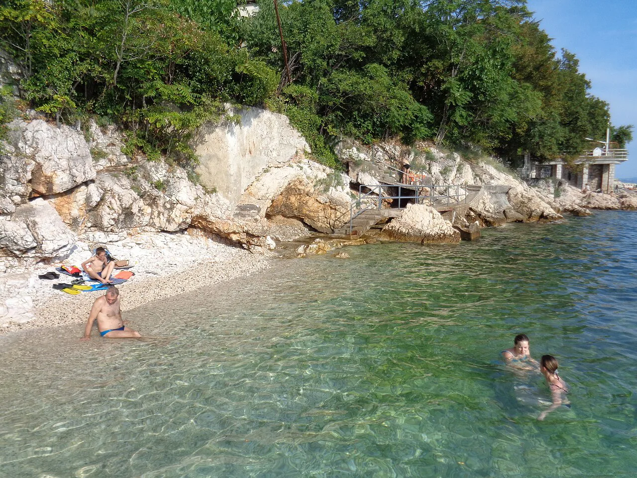 Swimmers in clear water at the rocky Glavanovo beach in Pećine, Rijeka
