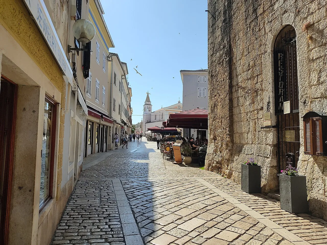 The Decumanus street in Poreč with the stone Pentagonal Tower on the right.