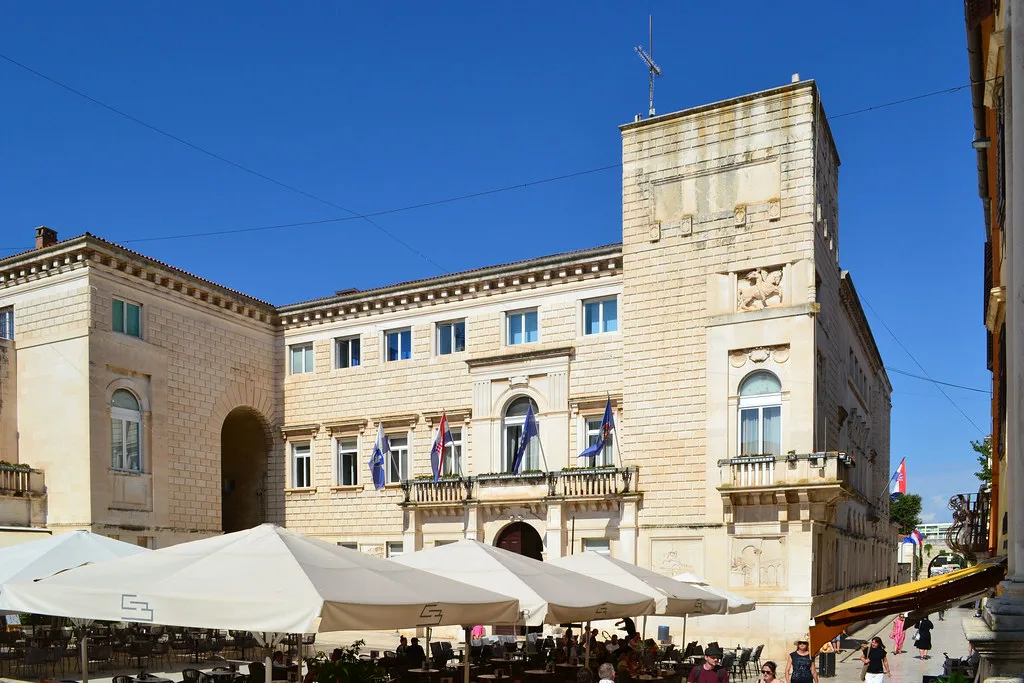 Stone buildings and café umbrellas on People's Square in Zadar