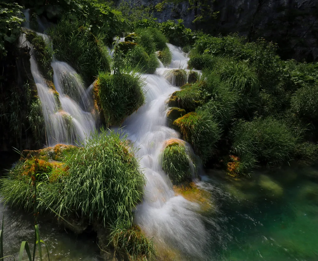 A waterfall tumbling through greenery in Plitvice Lakes National Park.