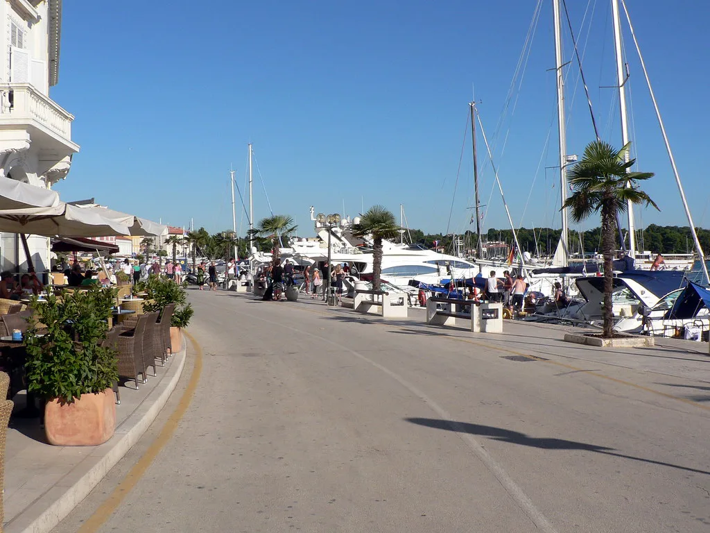 Café terraces and moored sailing boats along the waterfront promenade in Poreč