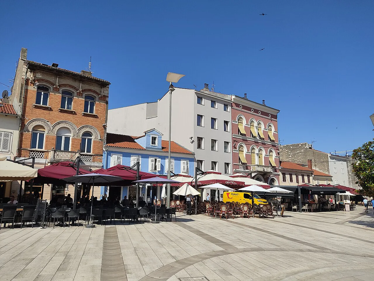 Café terraces and colourful buildings on a square in Poreč