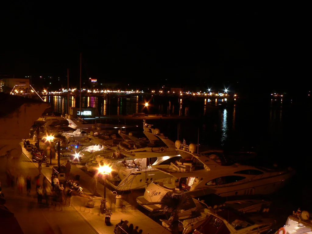 Boats moored along the lit Poreč waterfront at night