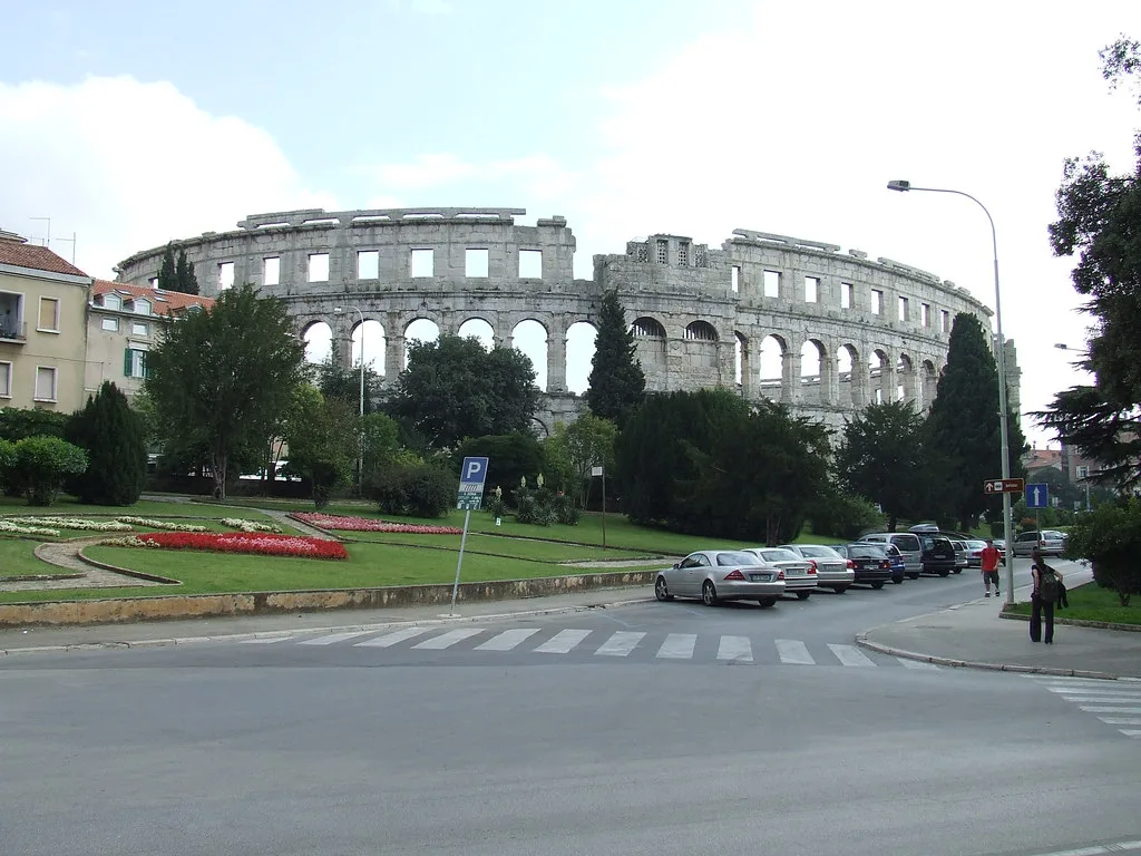The Roman amphitheatre in Pula seen across a park and road