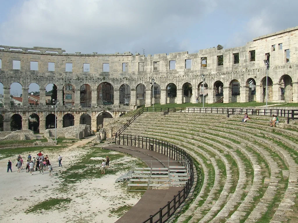 Visitors walking through the stone seating of the Roman amphitheatre in Pula