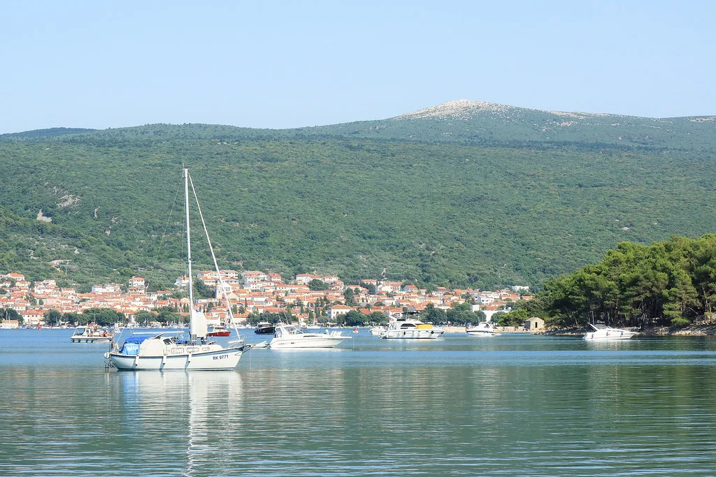 Sailing boats in the bay of Punat with green hills behind the town, Kvarner
