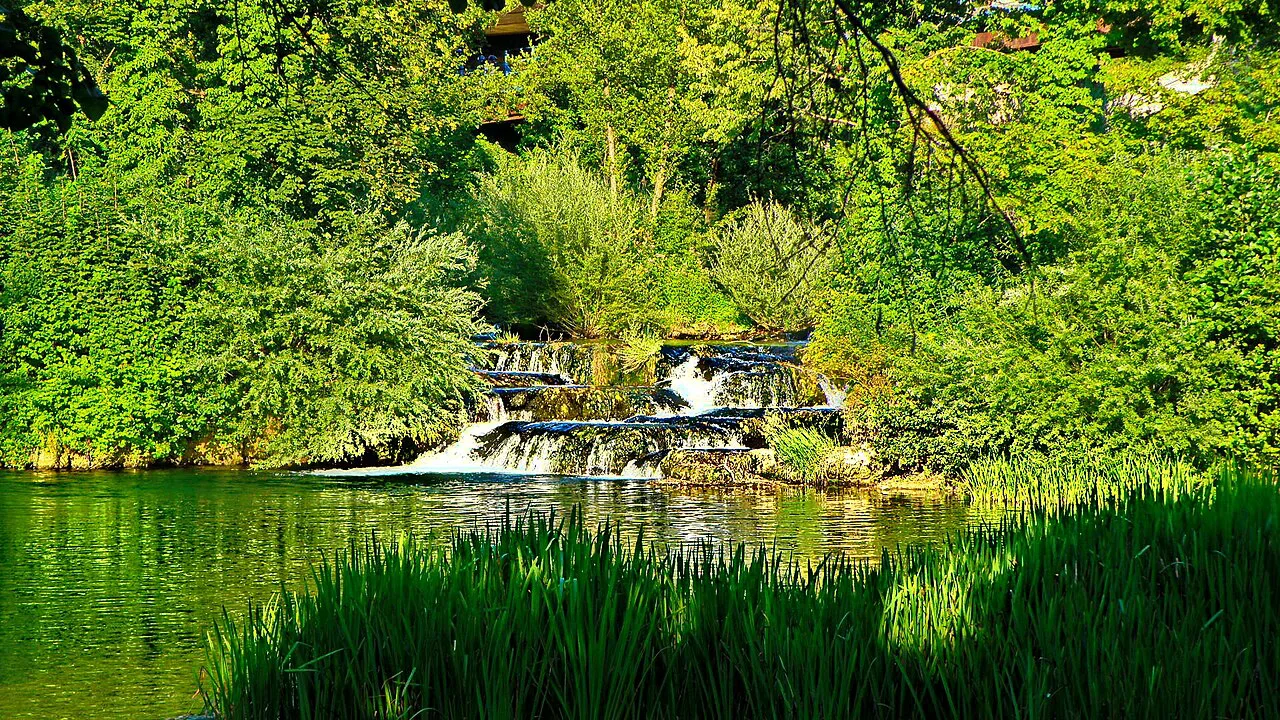 A small waterfall flowing into a green pool at Rastoke, Plitvice Lakes