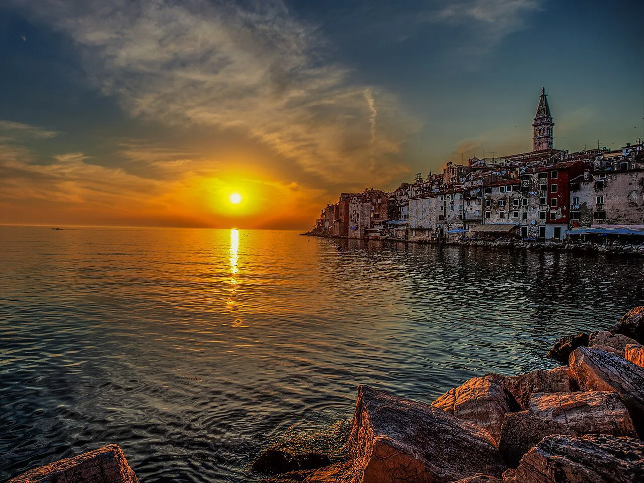 The sun setting over the sea beside the old town of Rovinj